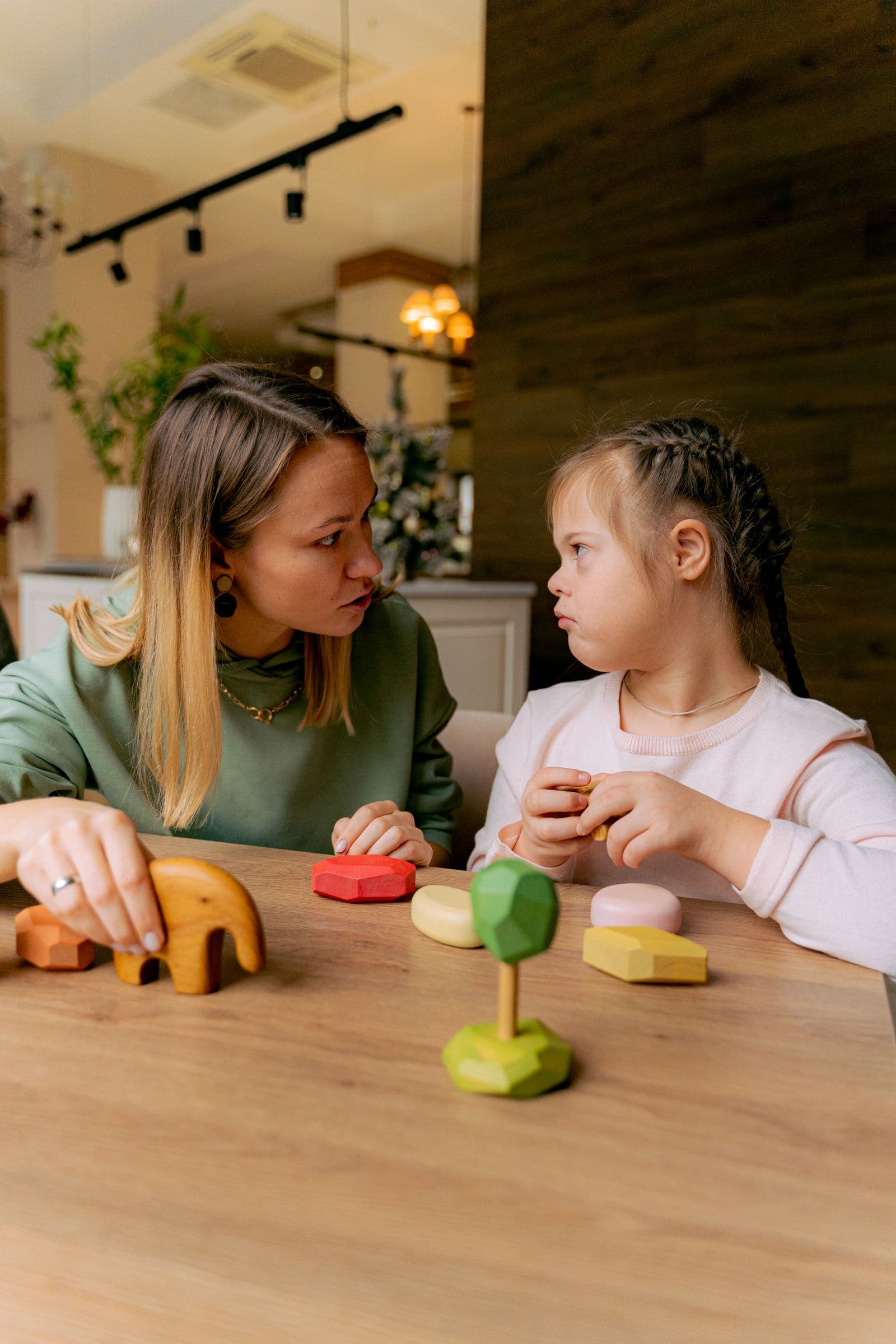 A speech therapist and a child working together with wooden toys at a table